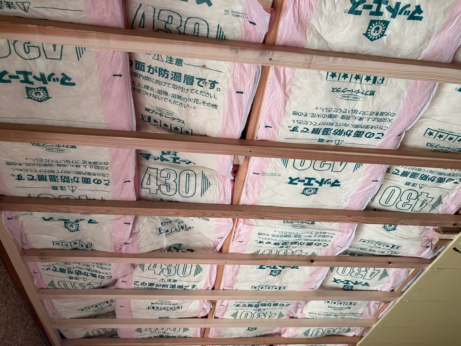 天井の下地に断熱材を敷き込んでいる様子