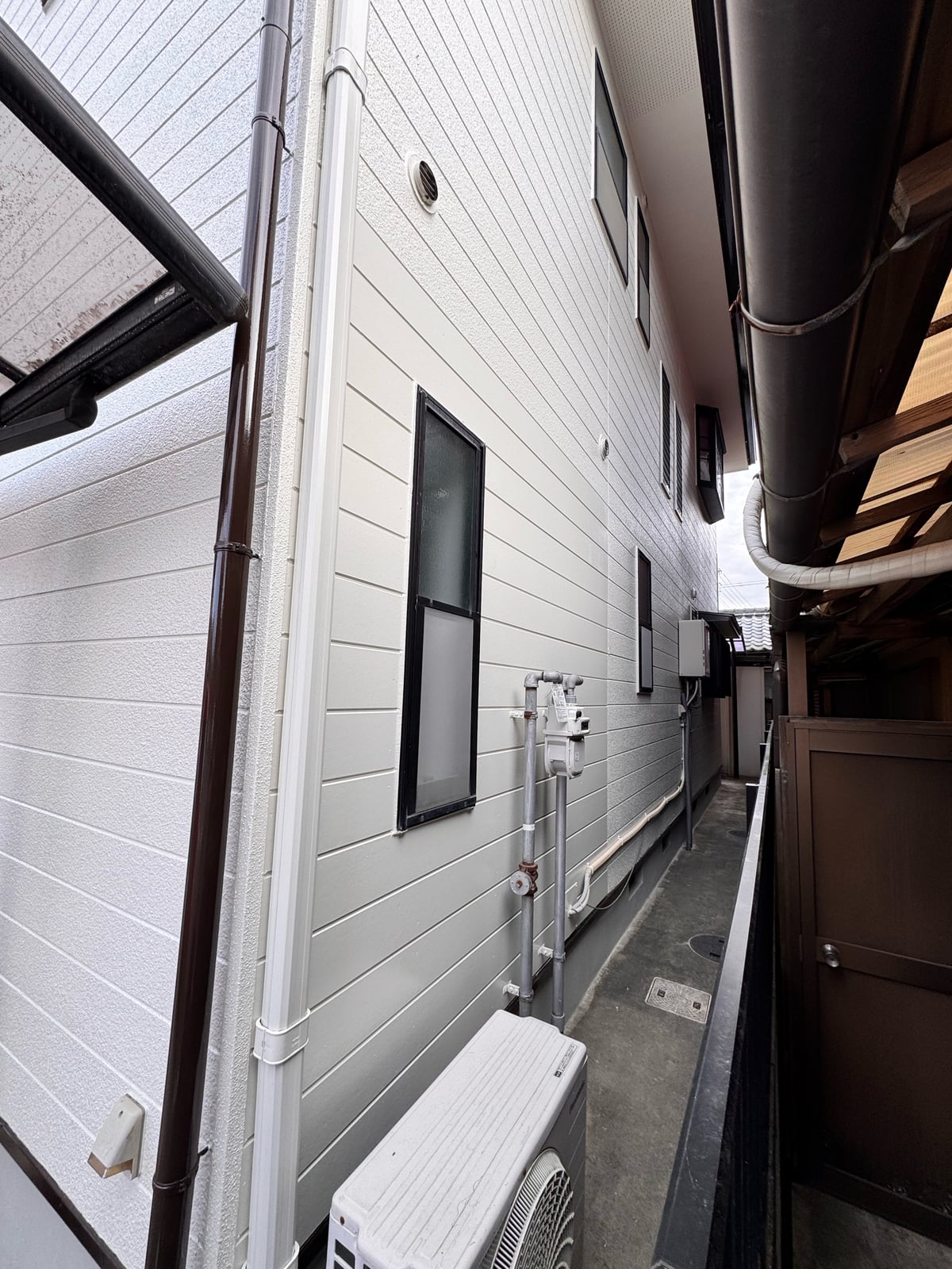 建物側面の通路から見上げた外壁。「パーフェクトトップSI 淡彩」の上品なテクスチャーが、住まい全体の印象を引き上げます。