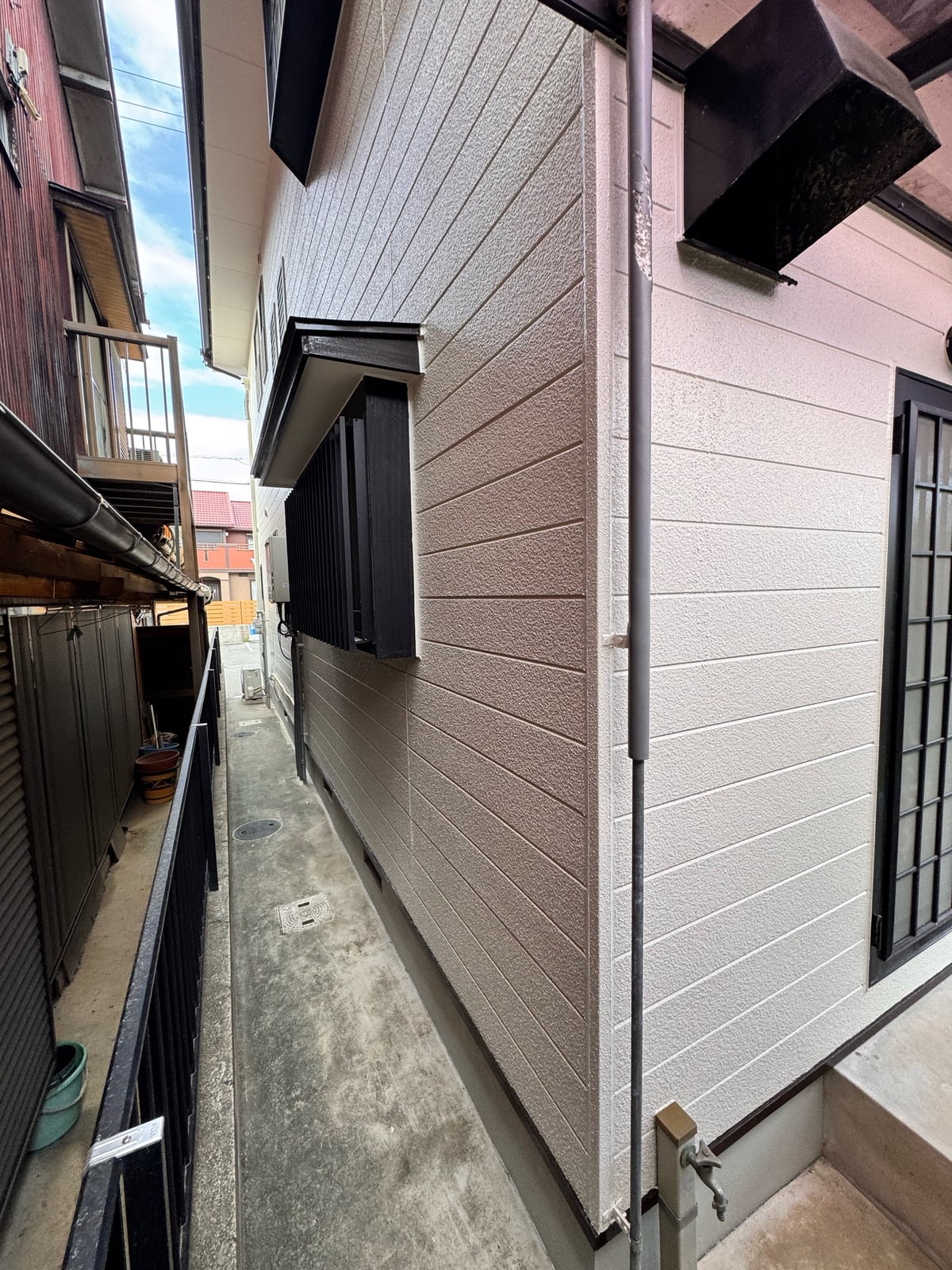 建物側面の外壁。淡いベージュ系の外壁色で、隣家との隙間にも光が回り込む明るい印象に仕上がりました。