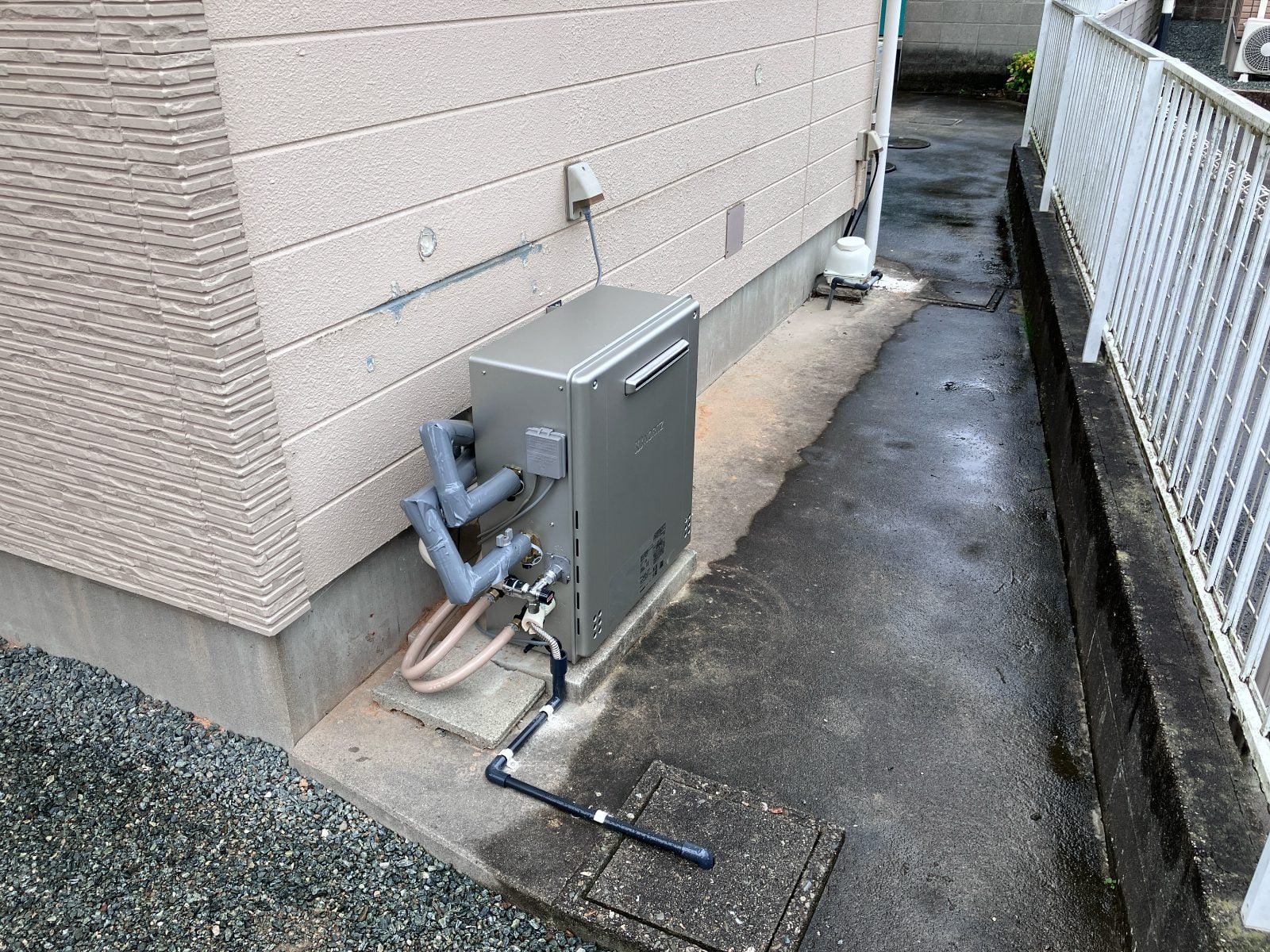 M様邸外壁側面に設置された給湯器。新規配管を含む設備工事の施工後写真です。