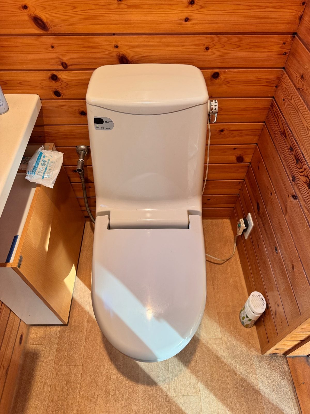 M様邸施工前のトイレ全体の様子。既存便器と木目調の壁・天井が確認できる施工前写真です。