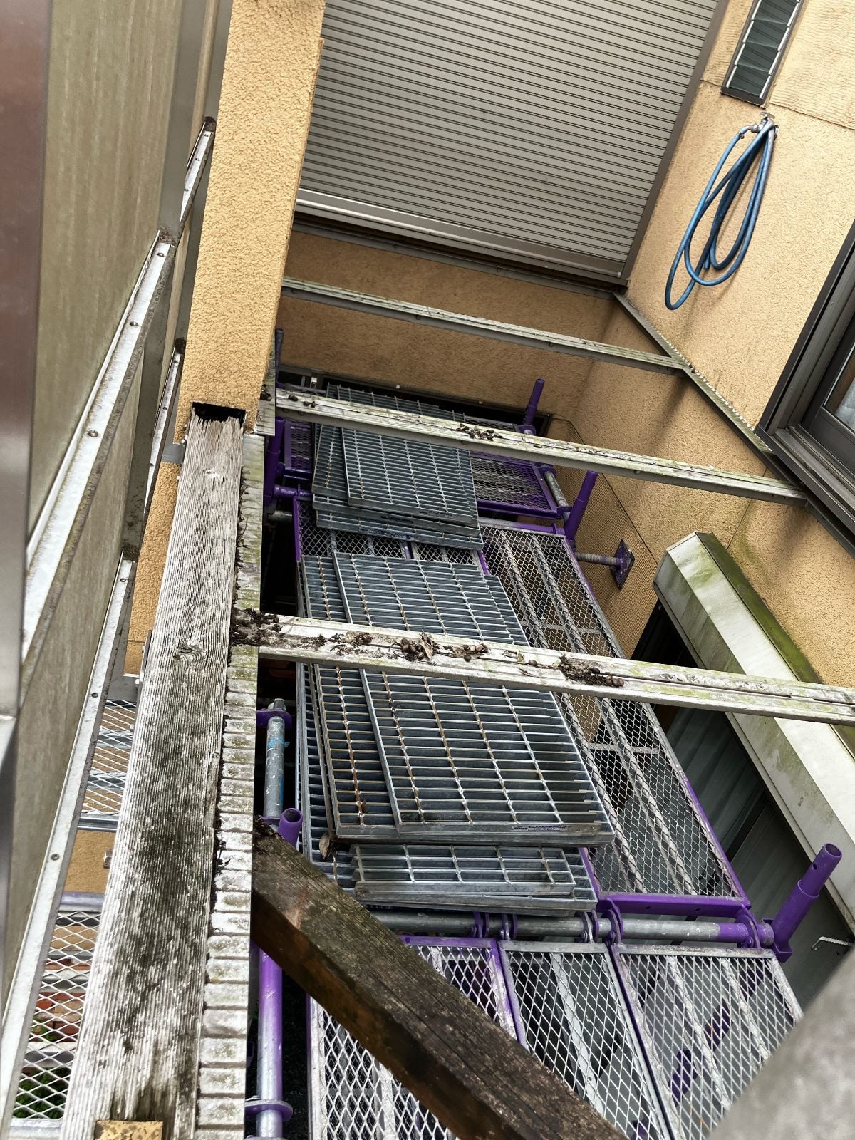 M様邸施工中、足場設置後のバルコニー周辺の様子。腐朽した木部と既存波板が露わになっています。
