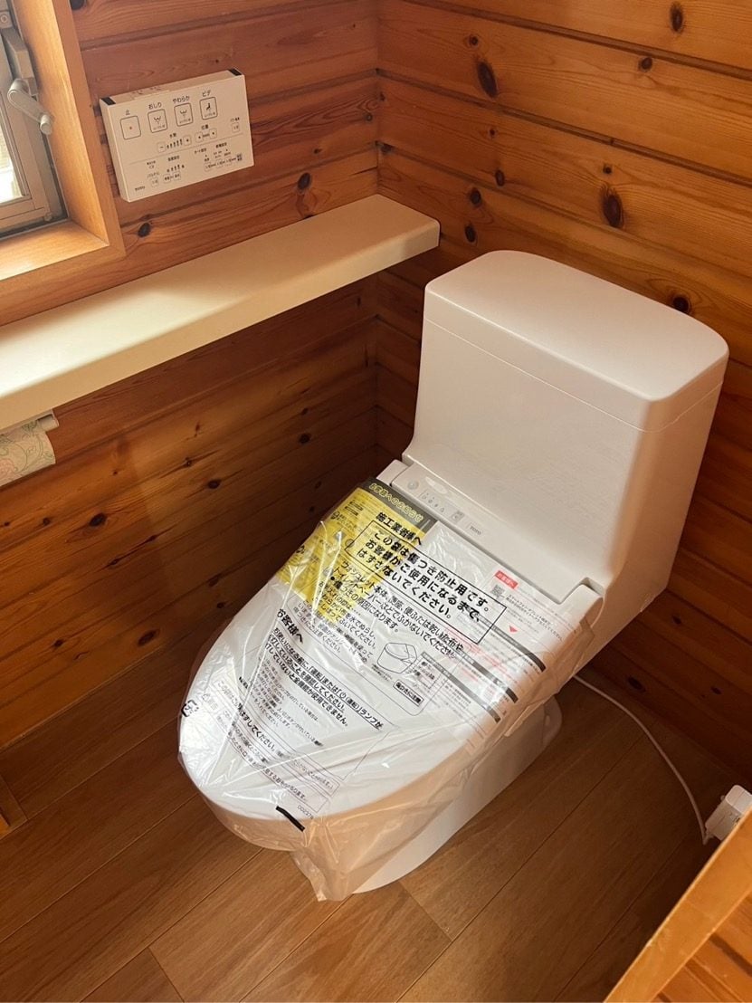M様邸施工後のトイレ全景。新品のウォシュレット一体型便器が木目調の空間に映えています。