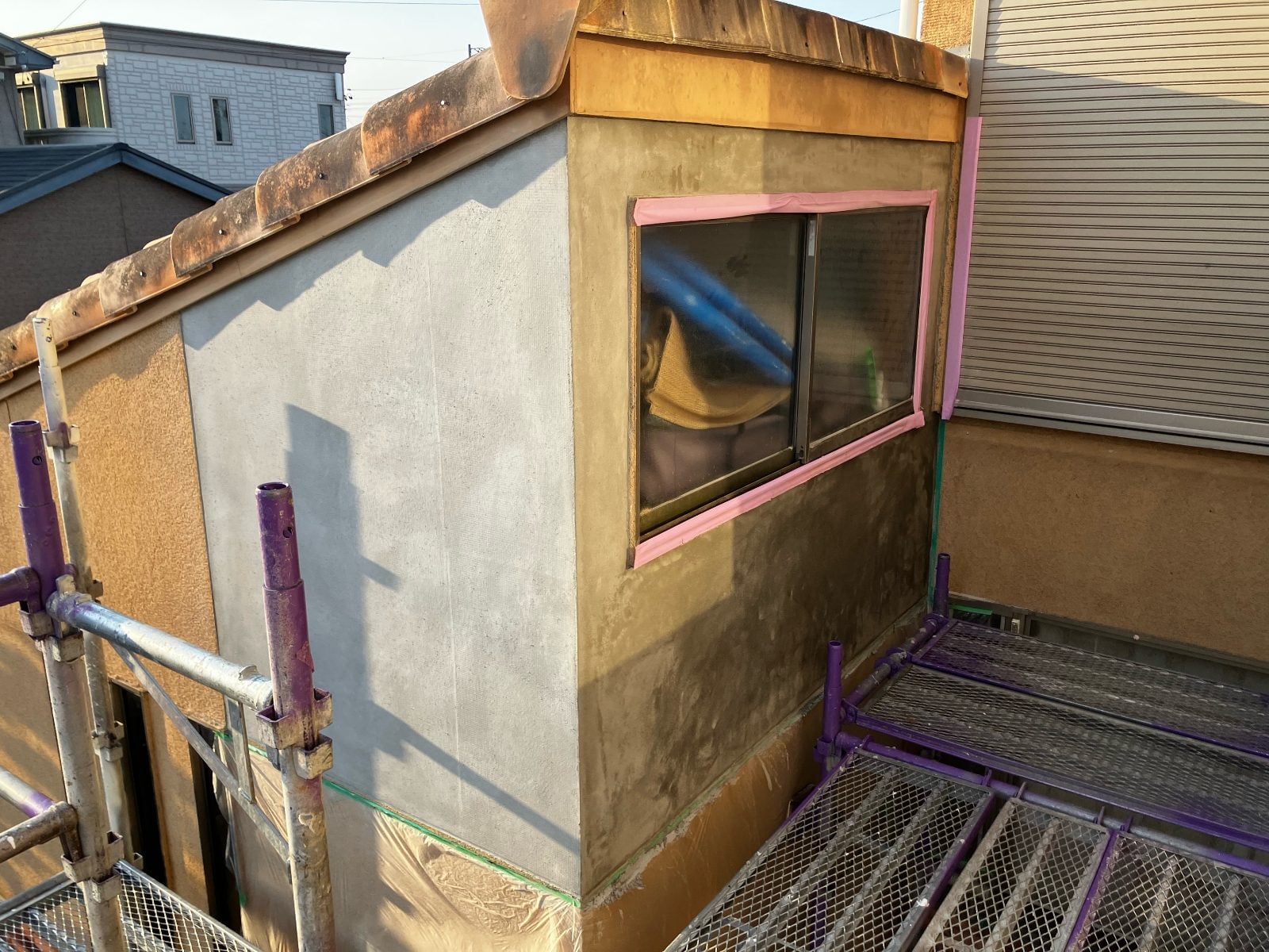 M様邸施工中の外壁コーナー部分にモルタル下塗りを施した様子。窓周りも丁寧に養生されています。