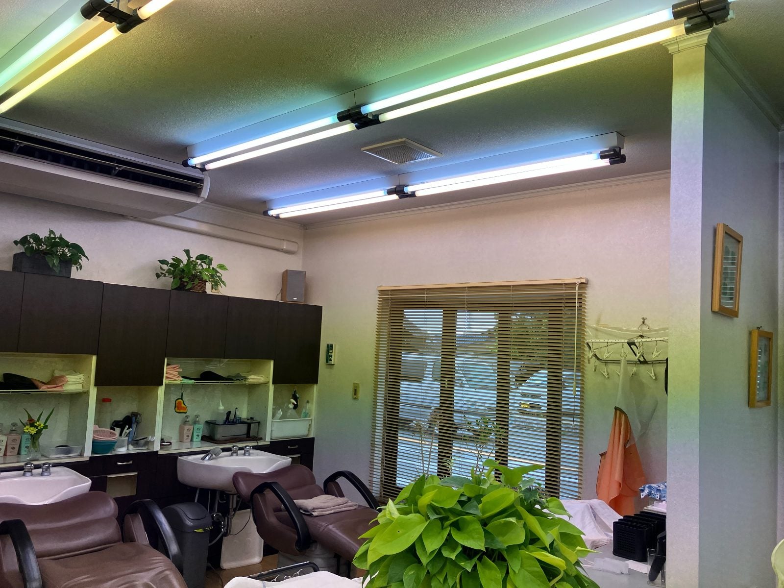 A様美容室シャンプーエリアの施工前の状況。蛍光灯の色ムラが壁・天井に広がっています