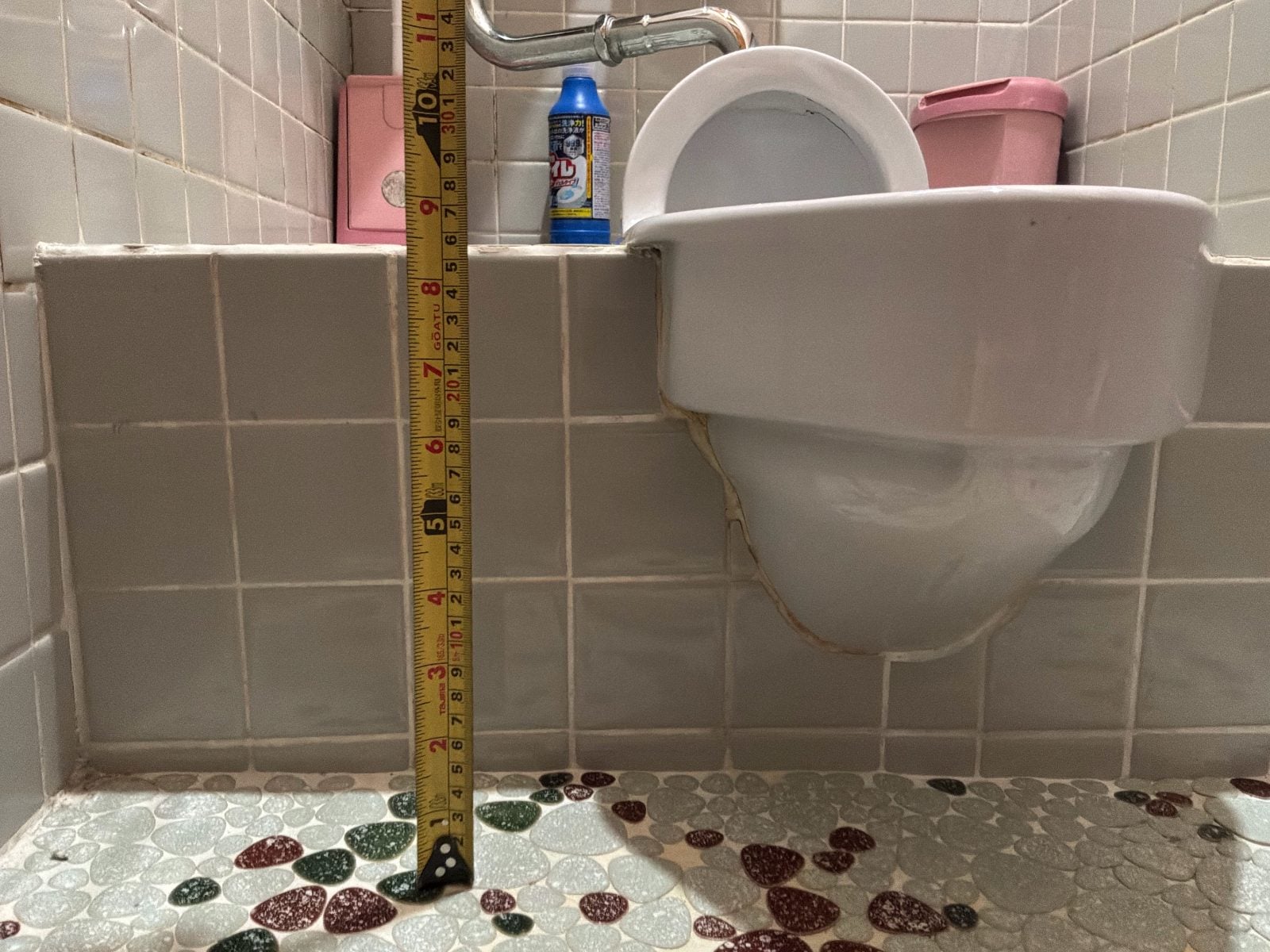 I様邸トイレ施工前の和式便器と壁タイル寸法確認。段差高さをスケールで記録した施工前資料です。