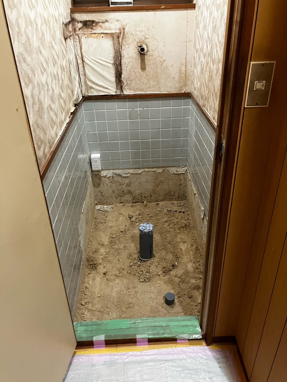 I様邸トイレ解体後の全景。床土間・排水管・壁クロスの剥がれが確認でき、下地の状態を記録しています。