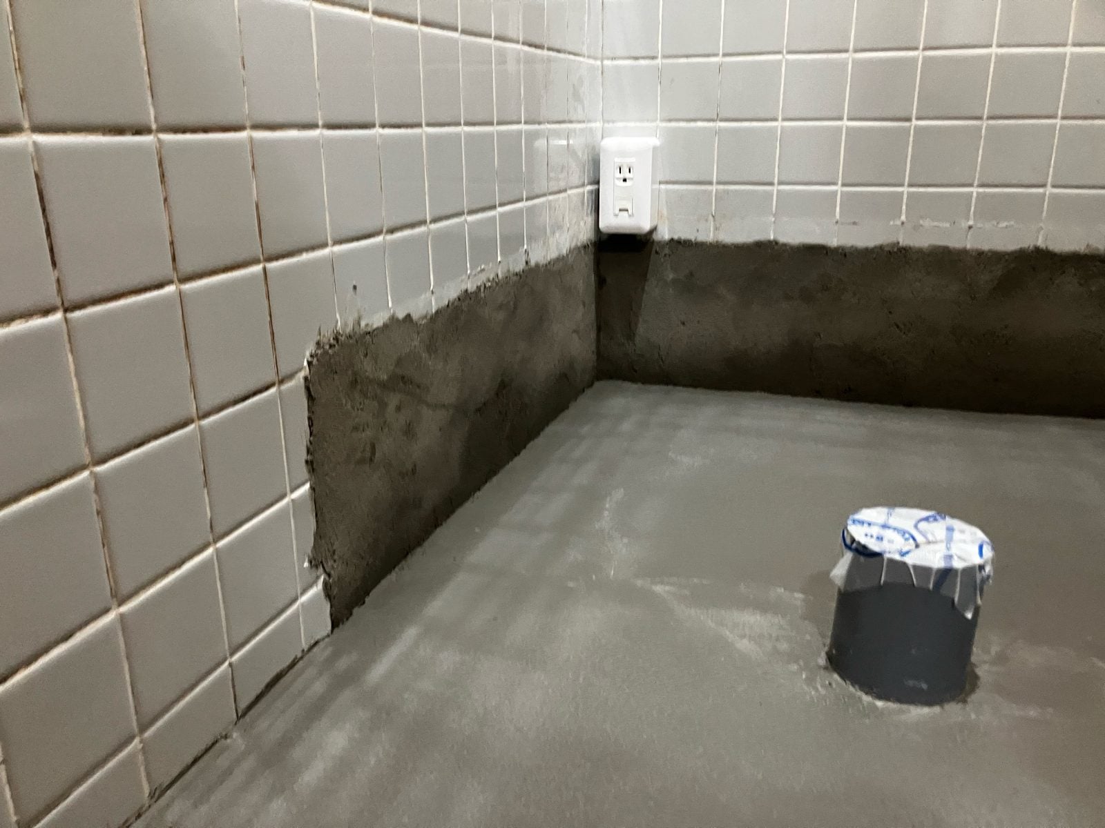 I様邸トイレ壁下地へのモルタル塗り付け作業中。既存タイルとの取り合い部分を丁寧に施工しています。